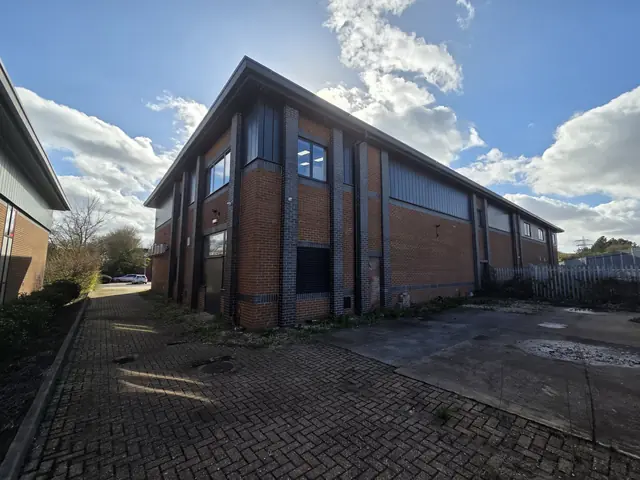 Side and rear elevation of the same two-storey brick-built industrial and office unit under a blue sky